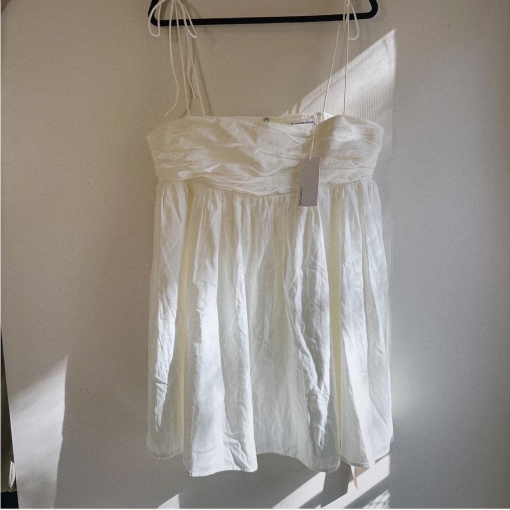 REFORMATION White mini dress with tie strap details and pleated bodice.